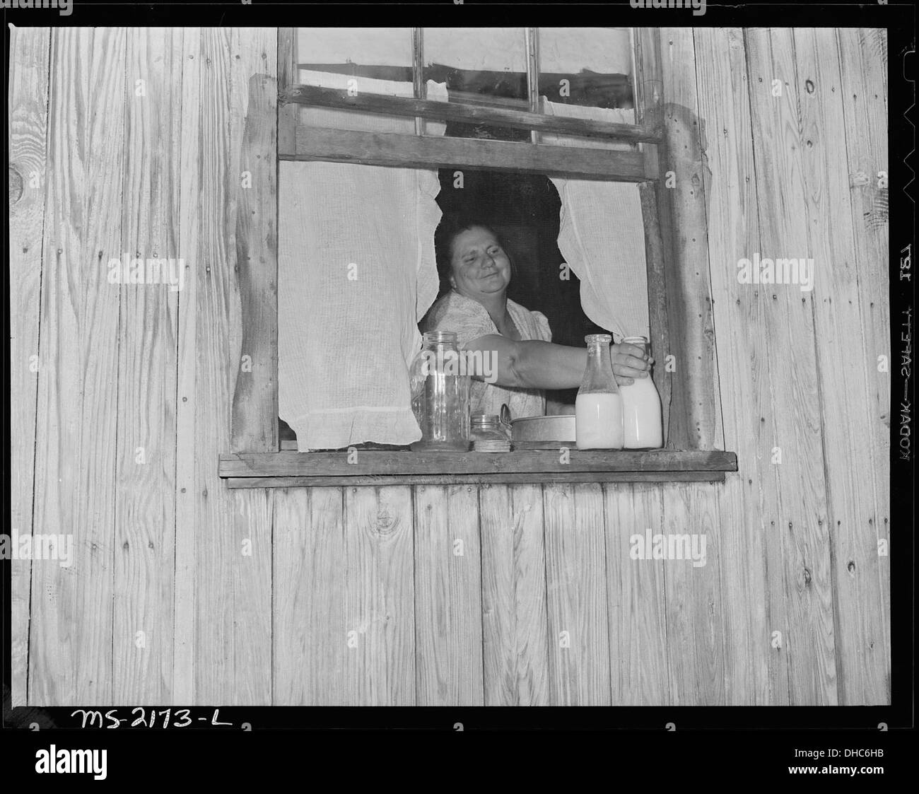 La signora Gillie Treadway, moglie di un minatore, recupera il latte dalla finestra della sua cucina in una casa senza refrigerazione. Questa fotografia riflette la vita in una comunità mineraria, evidenziando le sfide della vita quotidiana nelle aree rurali. Foto Stock