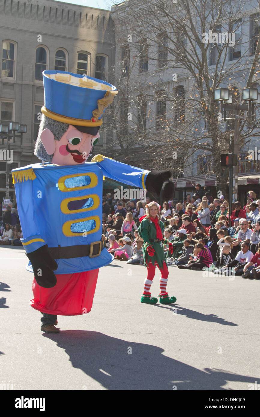 Un enorme stagno carattere soldato cammina accanto a un elfo in un Natale paeade in Asheville, North Carolina su Foto Stock