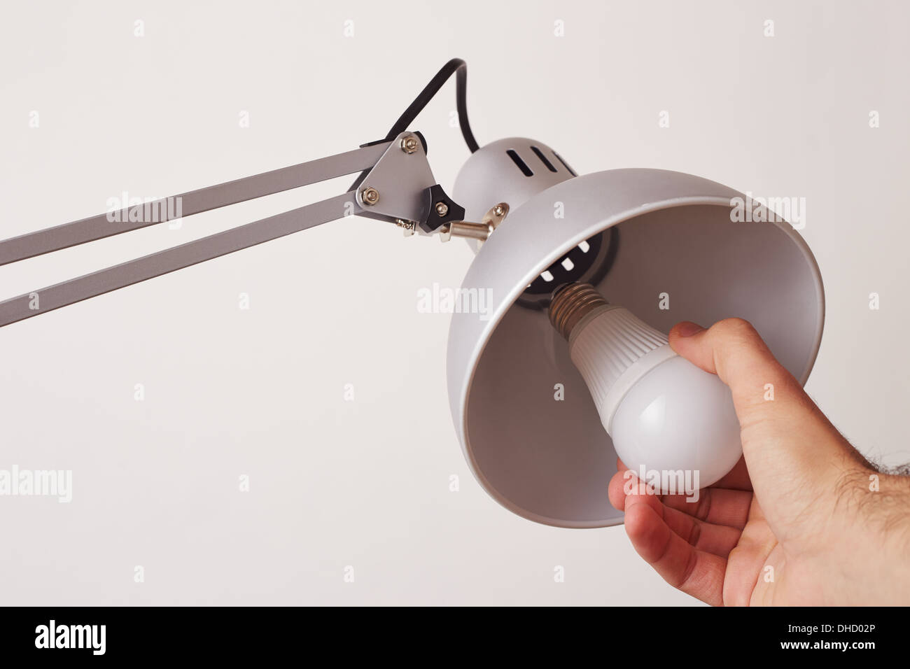 Mano la modifica di una normale lampadina a LED isolato su bianco Foto Stock