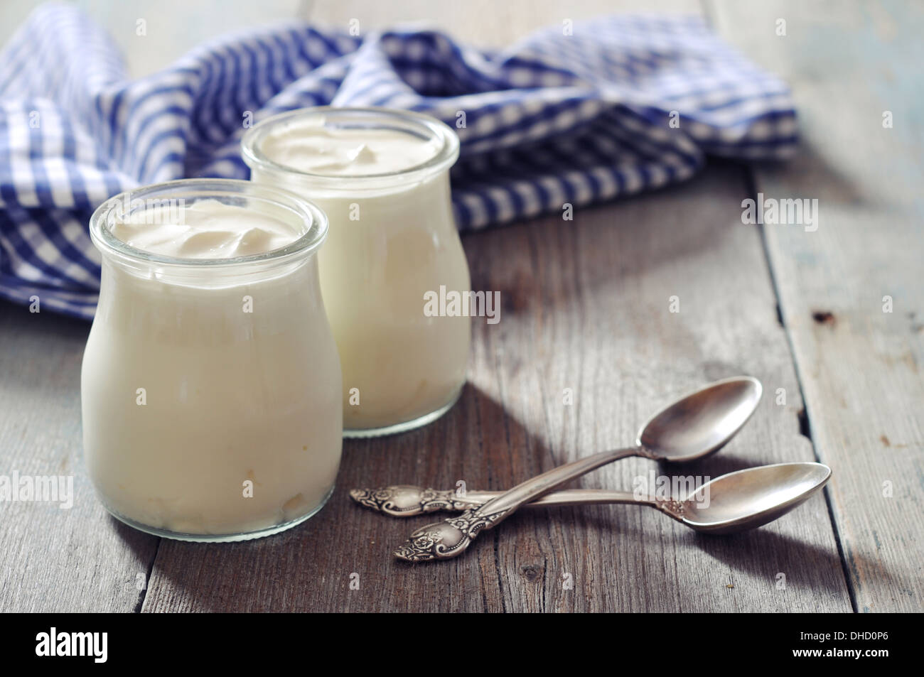 Lo yogurt greco in vasi di vetro con cucchiai su sfondo di legno Foto Stock