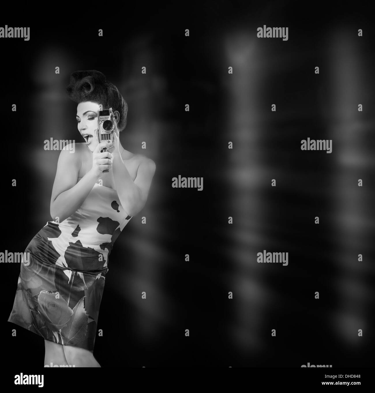 Una gara di misto modello europeo di età 20-25 fotografata in uno studio che indossa un abito di sfera e utilizzando un vintage 8mm/16mm fotocamera a pellicola. Foto Stock