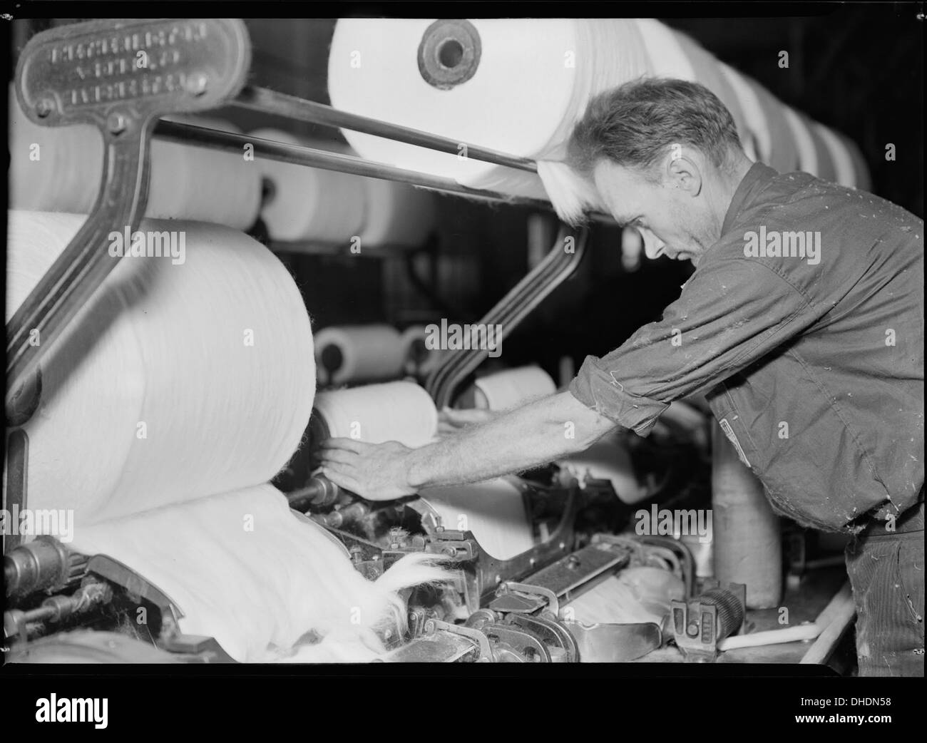 Un operatore altamente qualificato lavora una macchina complessa presso il Pickett Yarn Mill di High Point, North Carolina. Il mulino fa parte dell'industria tessile della regione, che ha giocato un ruolo chiave nella storia industriale degli Stati Uniti. Foto Stock