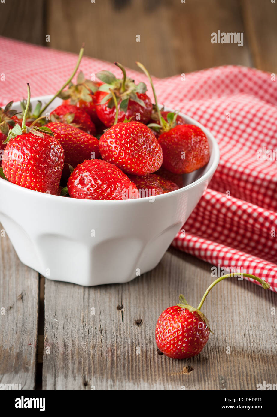 Le fragole in un recipiente su sfondo di legno Foto Stock