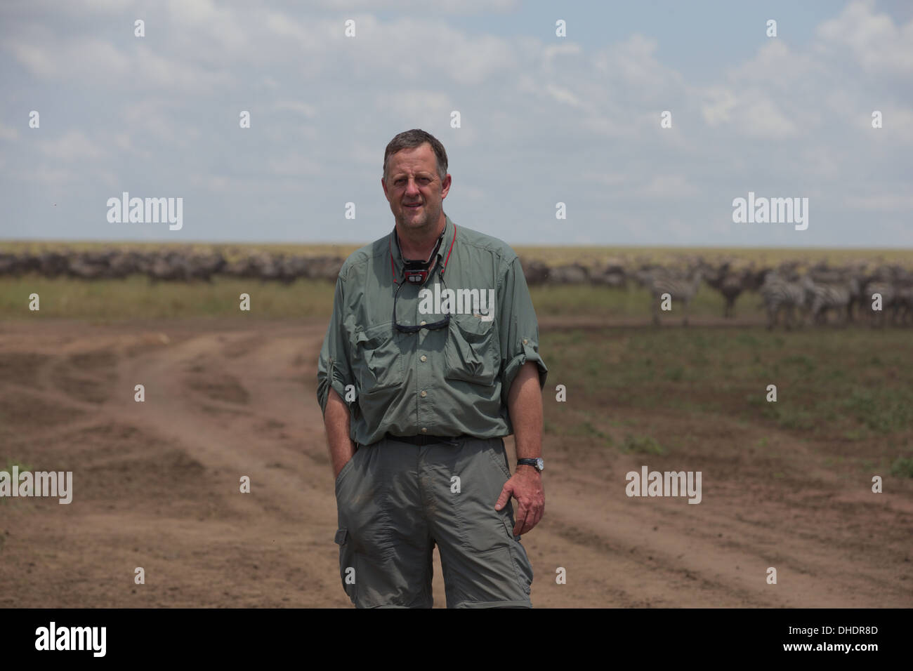 Fotografo Wayne Hughes piedi tra la migrazione di GNU. Le pianure del Serengeti. Tanzania, Africa. Foto Stock