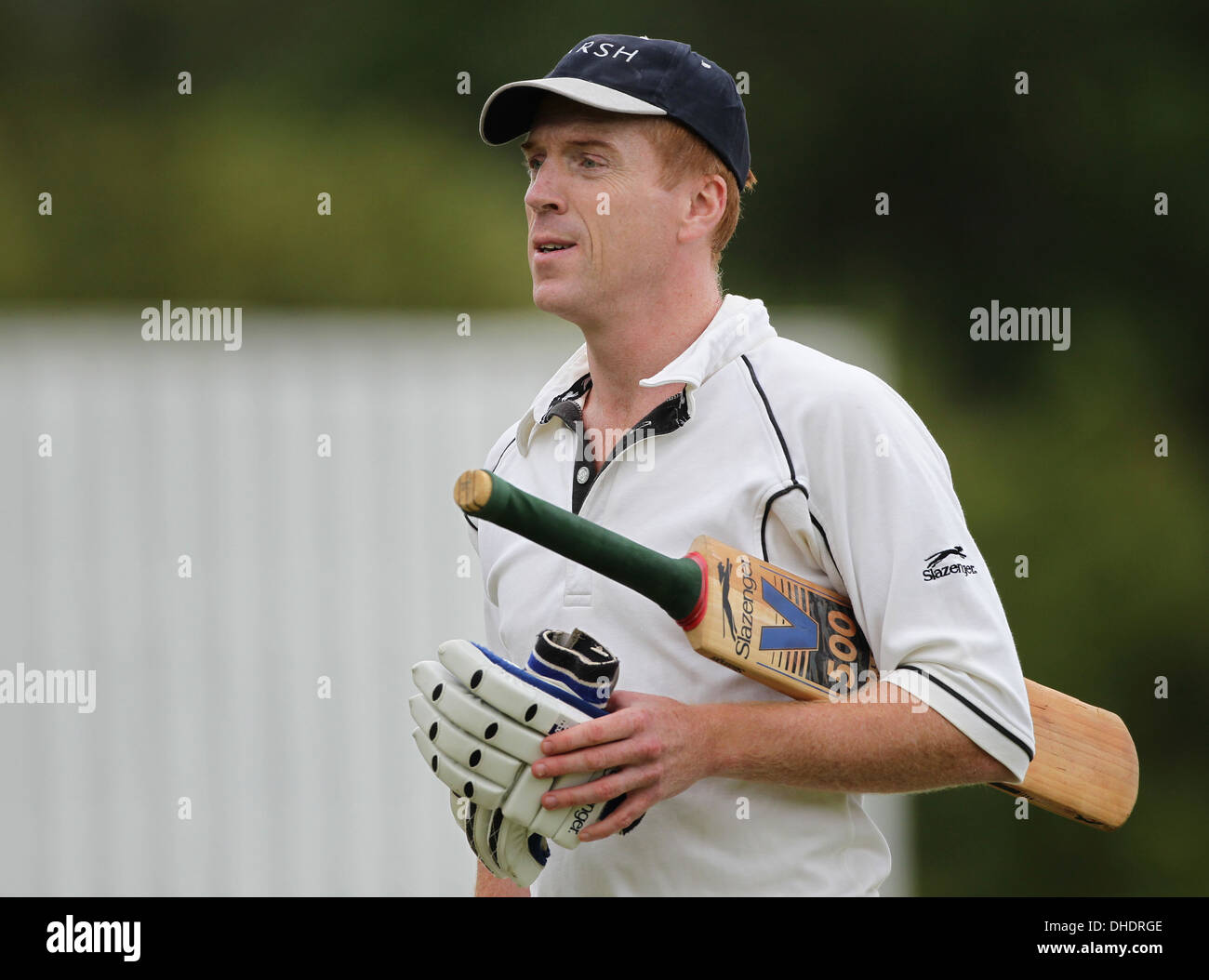 Attore Damian Lewis passeggiate fuori dal campo di cricket con i suoi guanti di cricket e il suo bat nascosto sotto il suo braccio. Foto Stock