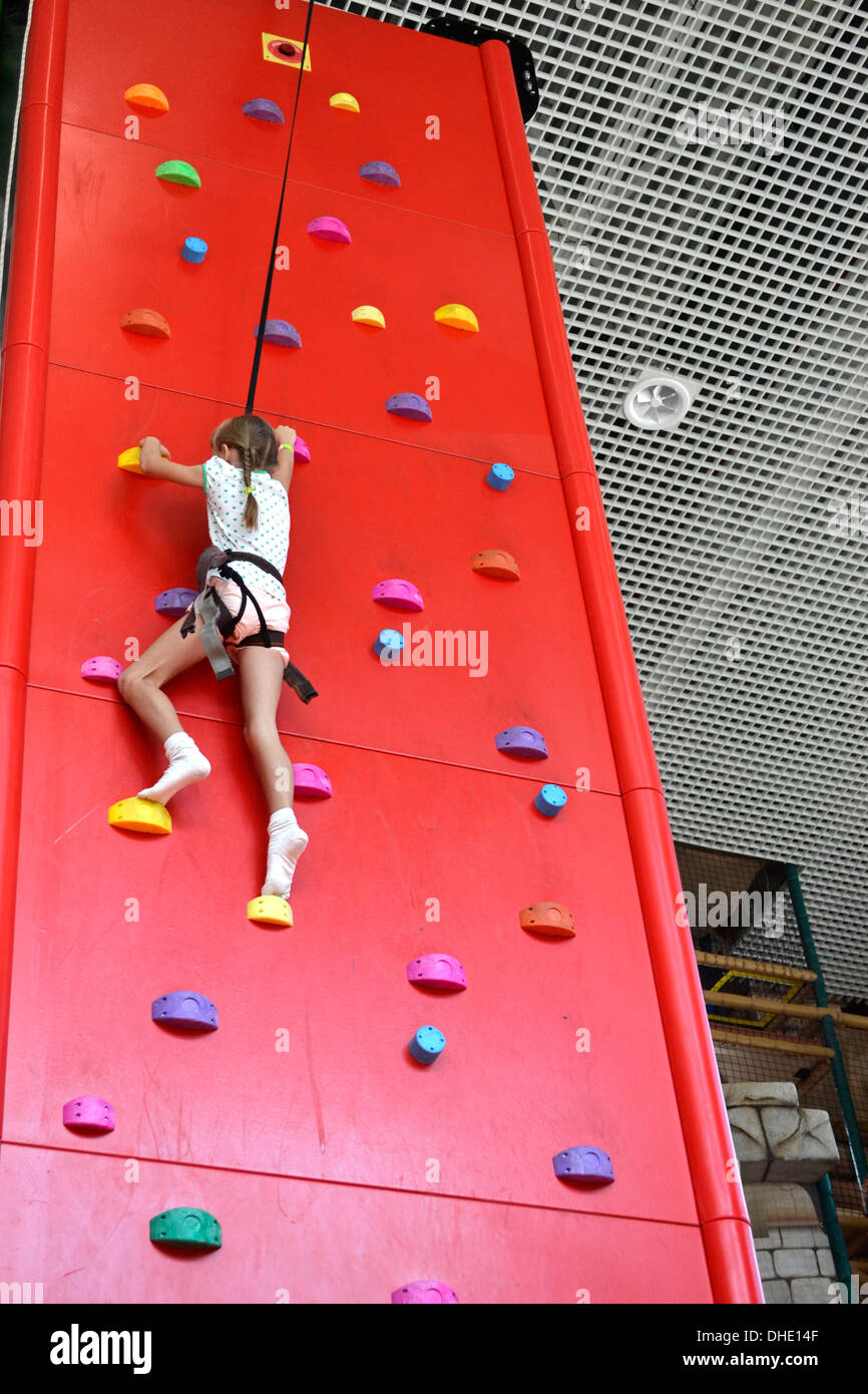 Bambina si inerpica su per la parete di arrampicata Foto Stock