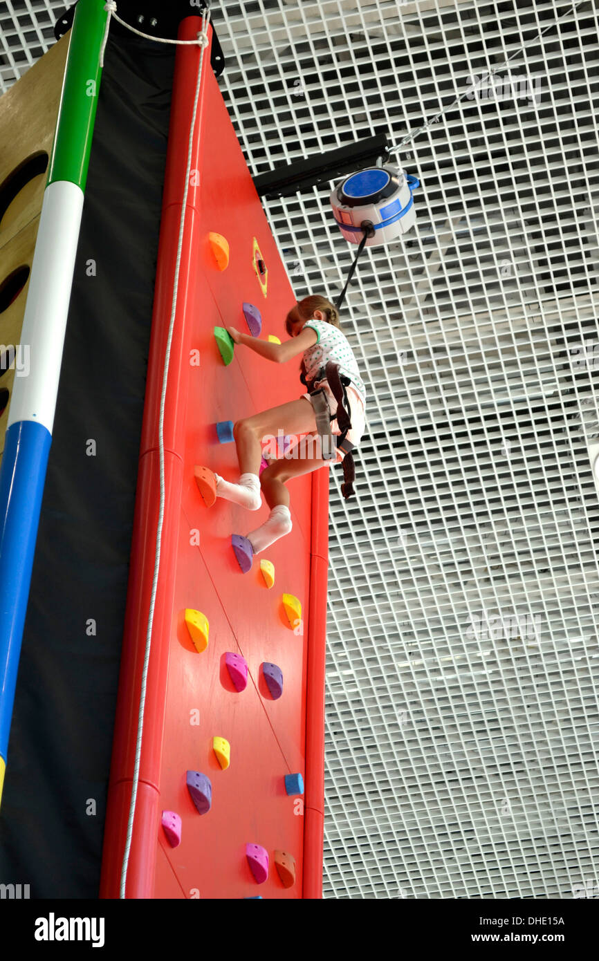 Bambina si inerpica su per la parete di arrampicata Foto Stock