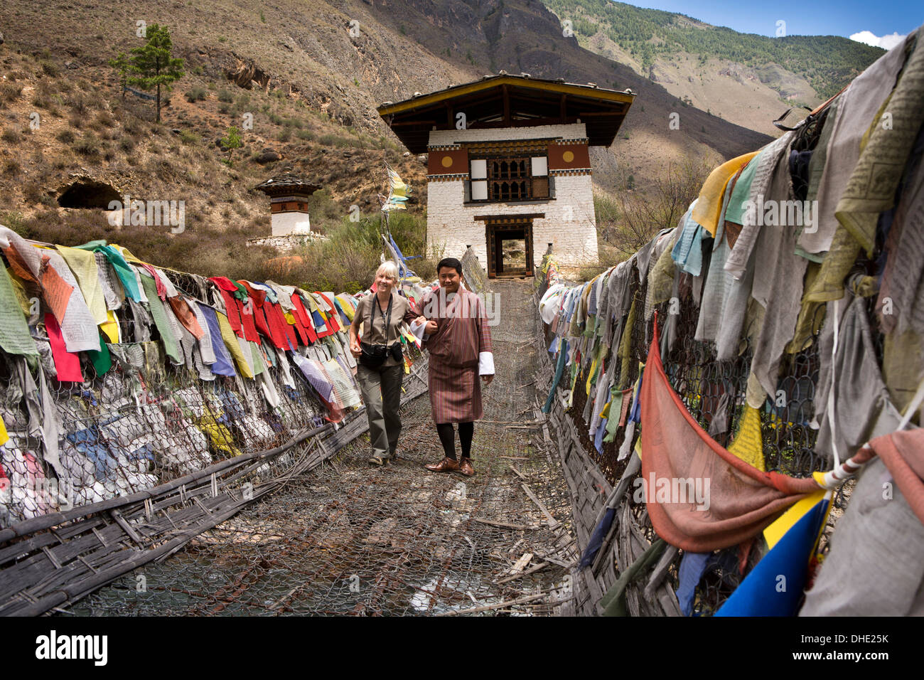Il Bhutan, Paro Valley, il turista femminile ha aiutato oltre Tachog Lhakang Dzong bridge, dalla guida Foto Stock