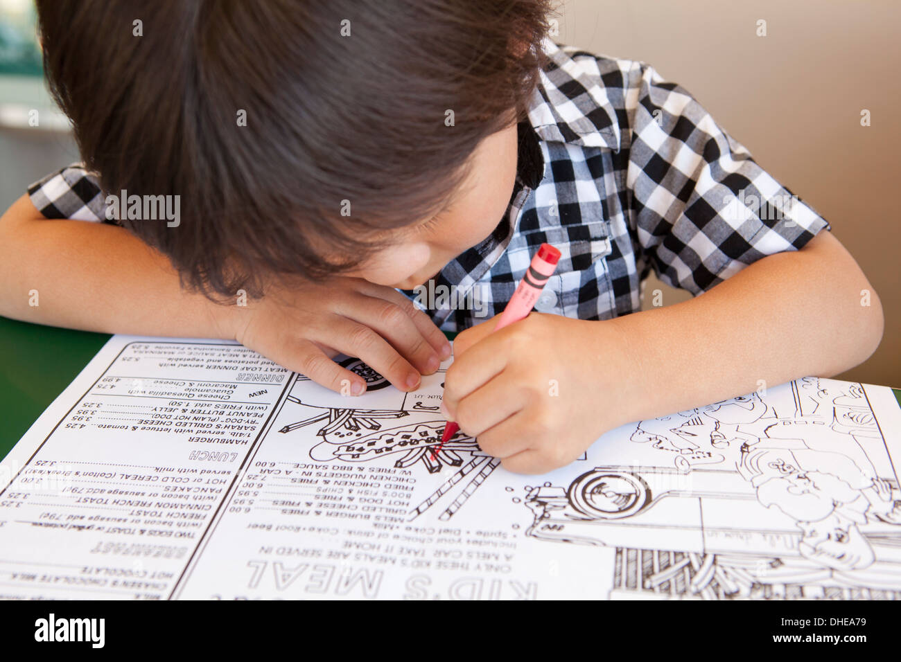 Primo piano di un giovane ragazzo la colorazione di un bambini's Diner menu Foto Stock
