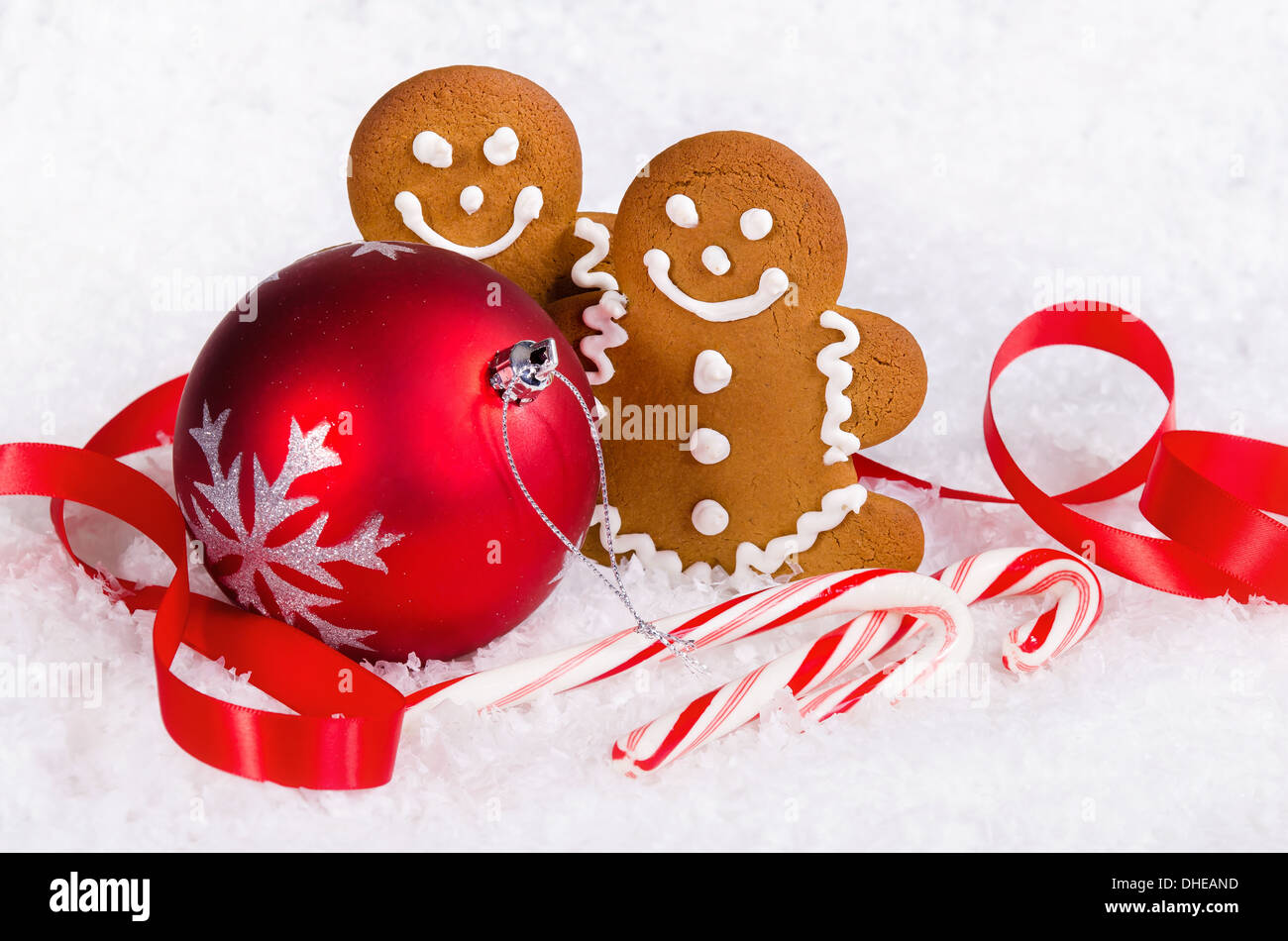 Gingerbread Man cookies e candy canes rosso con palla di Natale ornamento sulla neve sullo sfondo Foto Stock