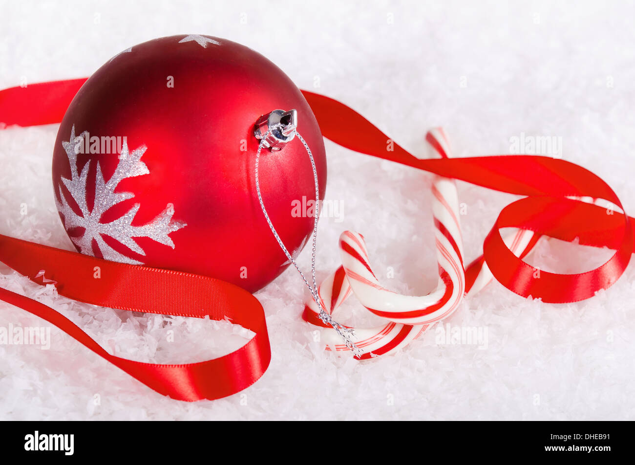 Candy canes rosso con palla di Natale ornamento e nastro su sfondo di neve Foto Stock