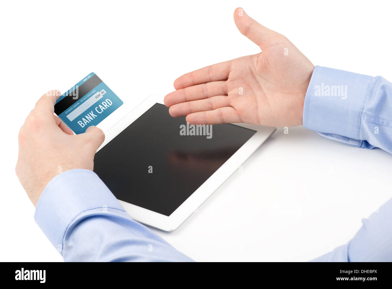 Mano d'uomo in possesso di una carta di credito su un tablet PC e l'altra mano dirigere verso lo schermo su uno sfondo bianco. Foto Stock