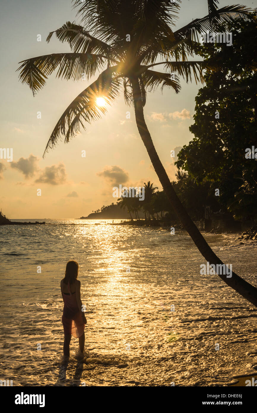 Una donna sotto una palma Mirissa sulla spiaggia al tramonto, costa meridionale dello Sri Lanka, a sud della provincia, Sri Lanka, Asia Foto Stock