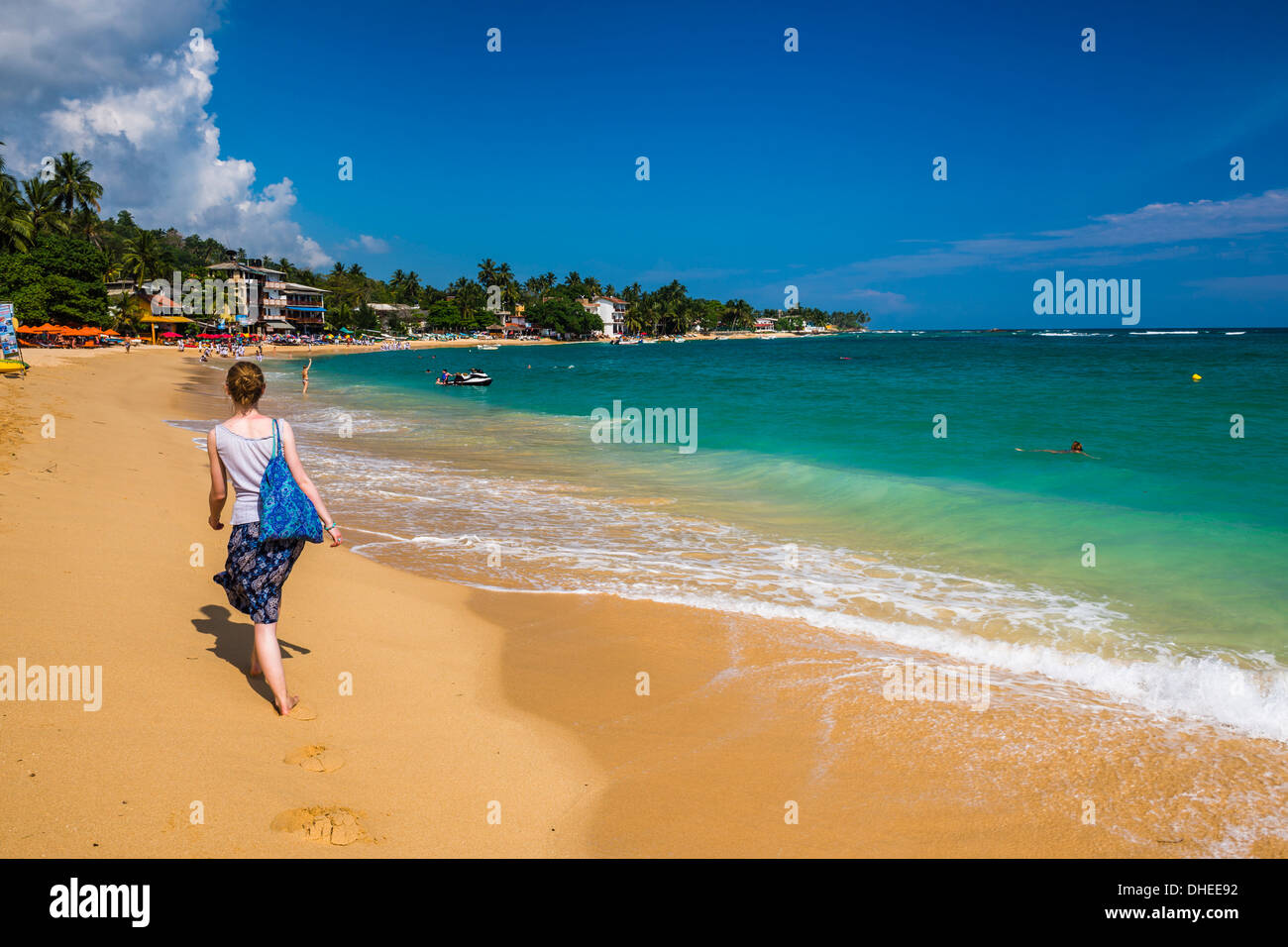 Tourist camminando lungo la spiaggia di Unawatuna, una bella spiaggia di sabbia sulla costa sud dello Sri Lanka, in Asia Foto Stock