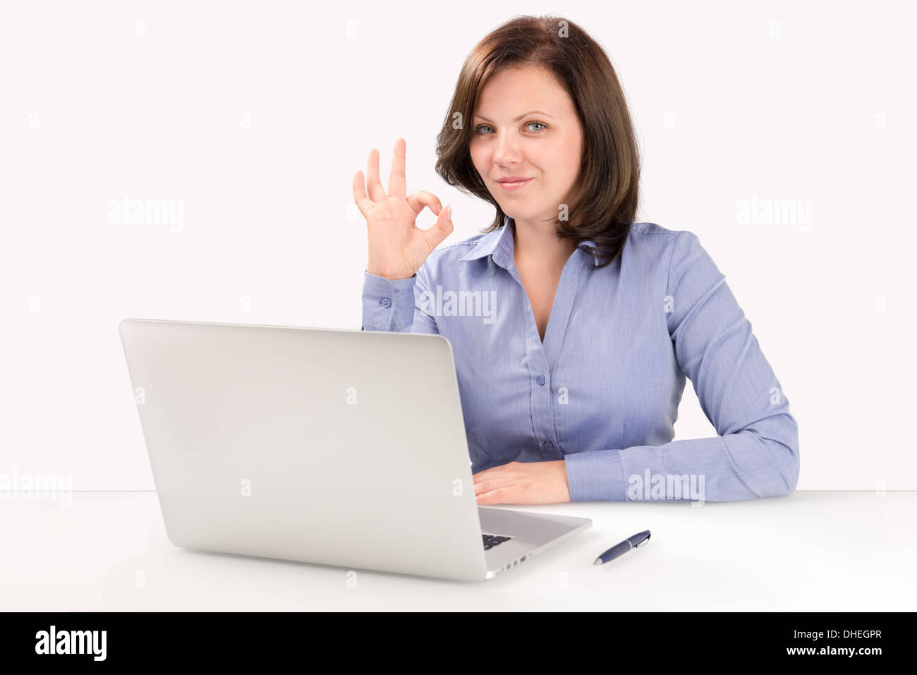 Imprenditrice è seduta davanti a un laptop moderno e mostrando ok gesto, la concezione di business Foto Stock