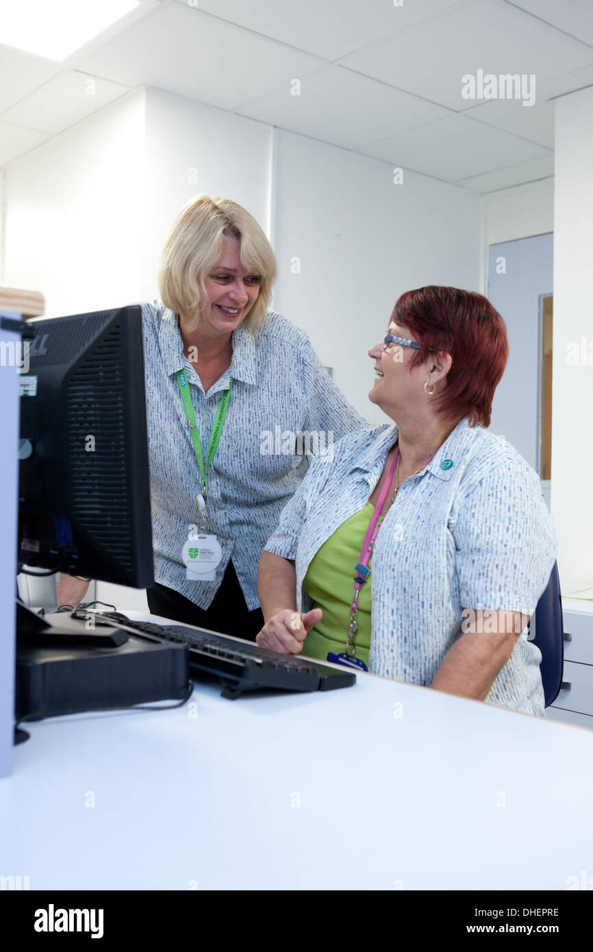 Hospital receptionist controllare gli appuntamenti in un depatment ambulatoriale REGNO UNITO Foto Stock