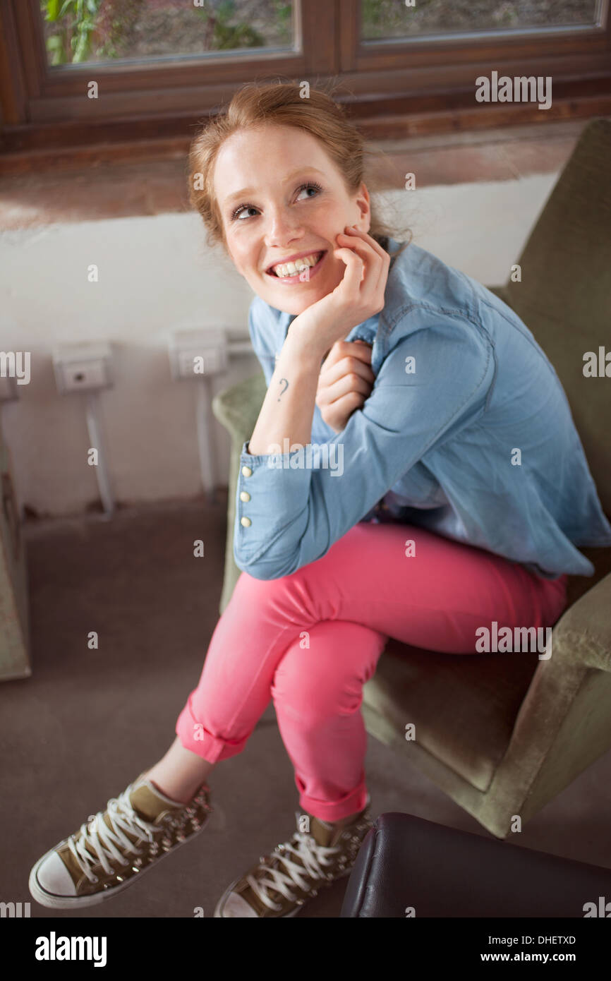 Giovane donna seduta con le gambe incrociate Foto Stock