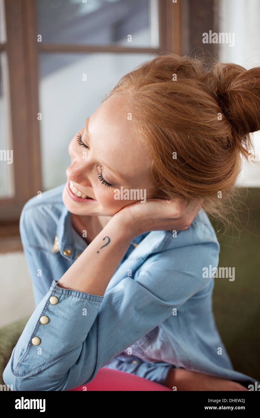 Giovane donna con punto interrogativo tattoo sorridente Foto Stock