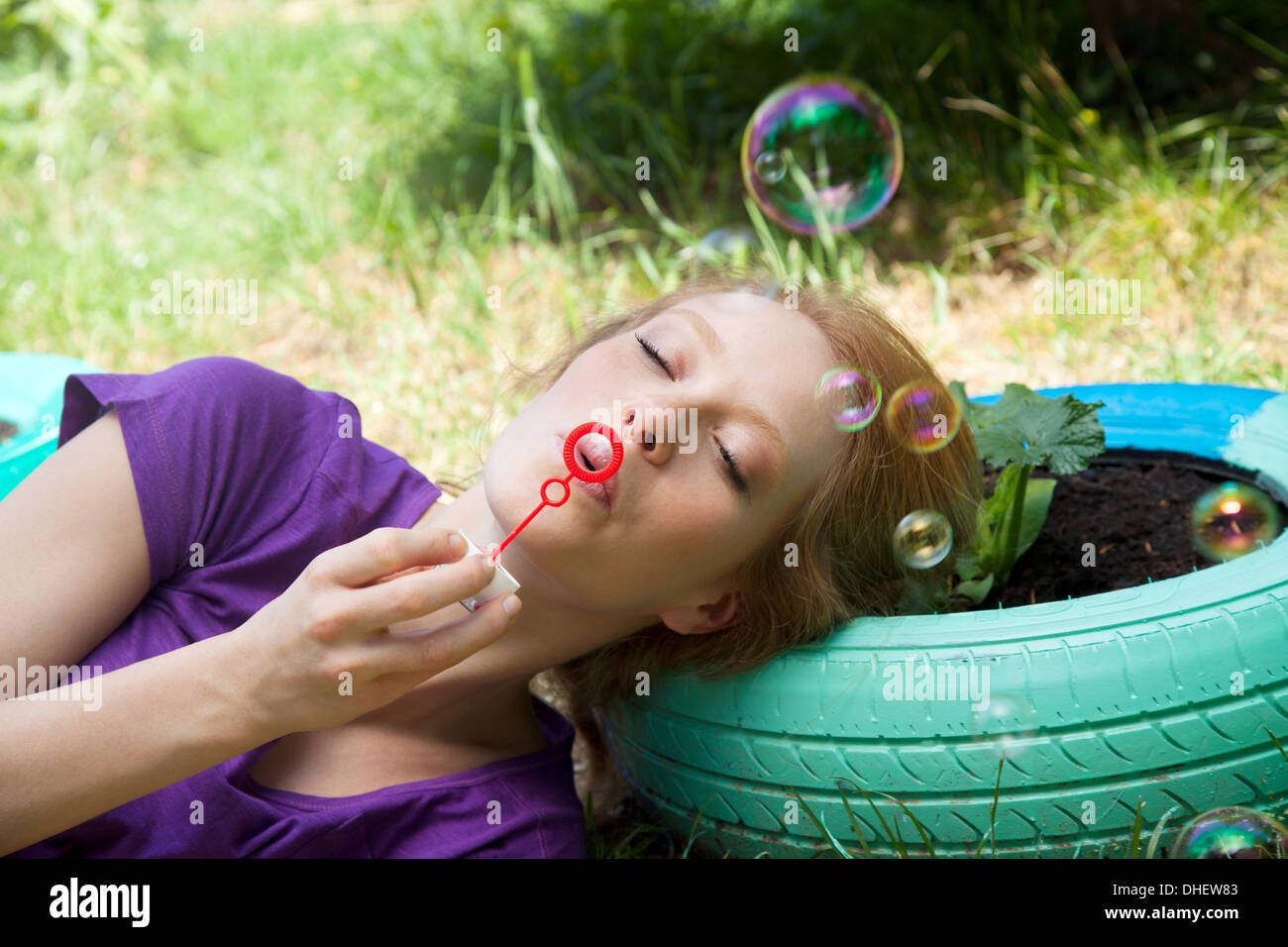 Donna sdraiata sul pneumatico a soffiare bolle Foto Stock