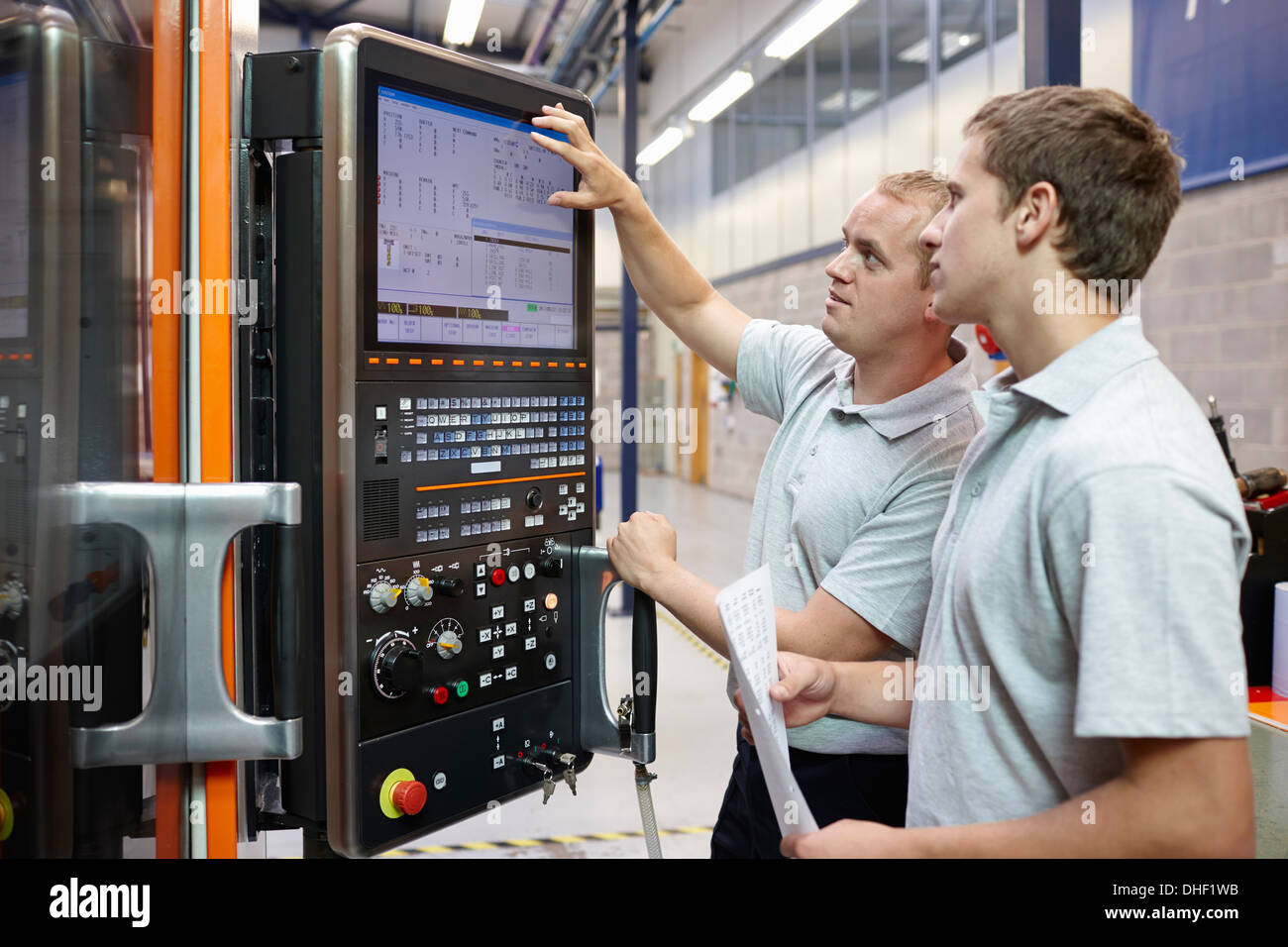 Lavoratori guardando il monitor di un computer nella fabbrica di ingegneria Foto Stock