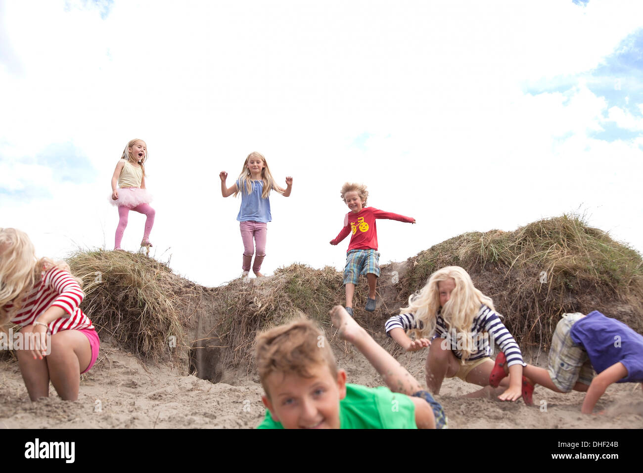 Gruppo di bambini salta fuori da dune di sabbia, Wales, Regno Unito Foto Stock
