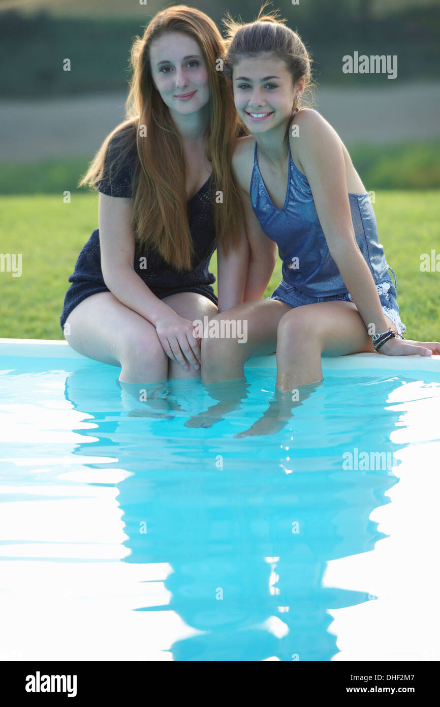 Due ragazze adolescenti seduti a bordo piscina, Toscana, Italia Foto Stock