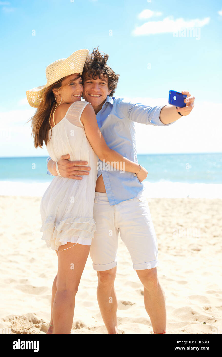 Giovane self fotografare con il telefono cellulare sulla spiaggia Foto Stock