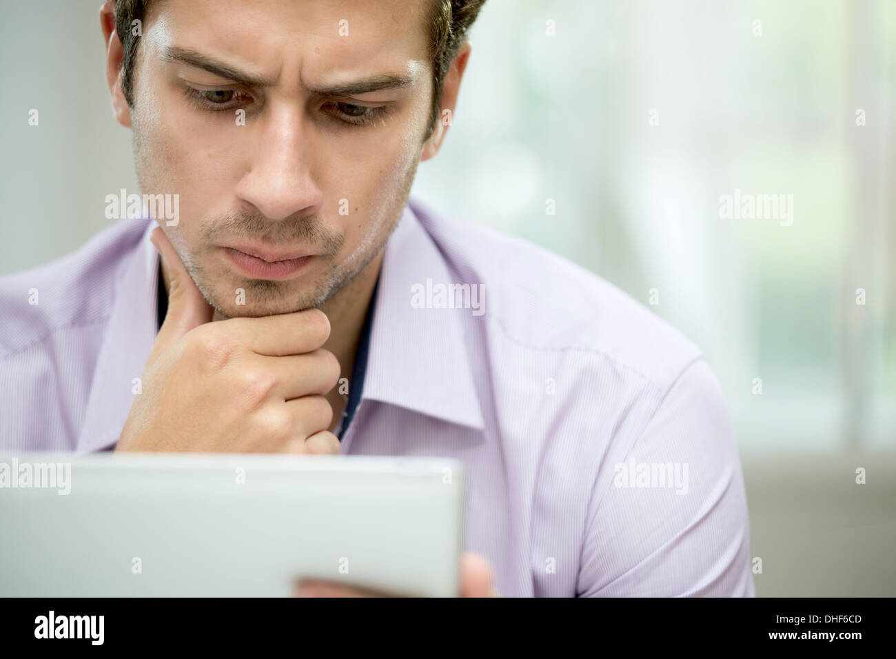 Giovane uomo guardando il messaggio sulla tavoletta digitale Foto Stock