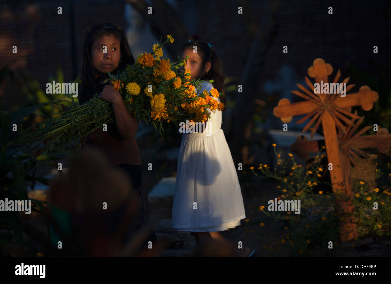 Una donna porta calendula fiori durante il giorno dei morti celebrazioni nel cimitero di Santa Ana Zegache, Oaxaca, Messico Foto Stock