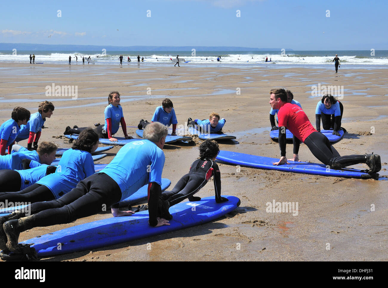 Nonno e nipote sulla stessa scheda avente lezioni di surf sulla spiaggia e apprendimento della 'pop-up' sulla scheda Foto Stock