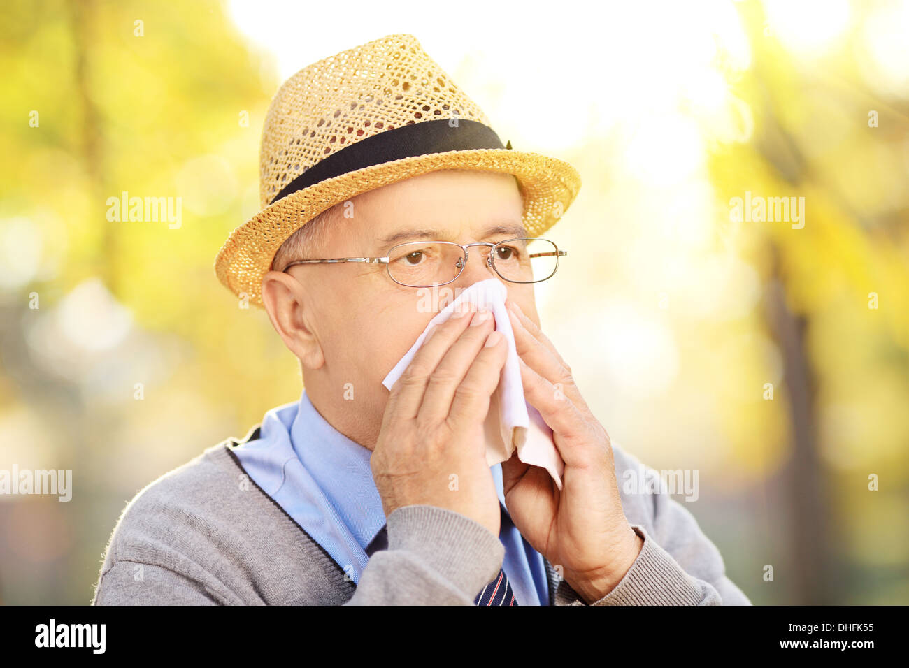 Uomo maturo soffia il naso in carta tissue a causa di malattia al di fuori Foto Stock