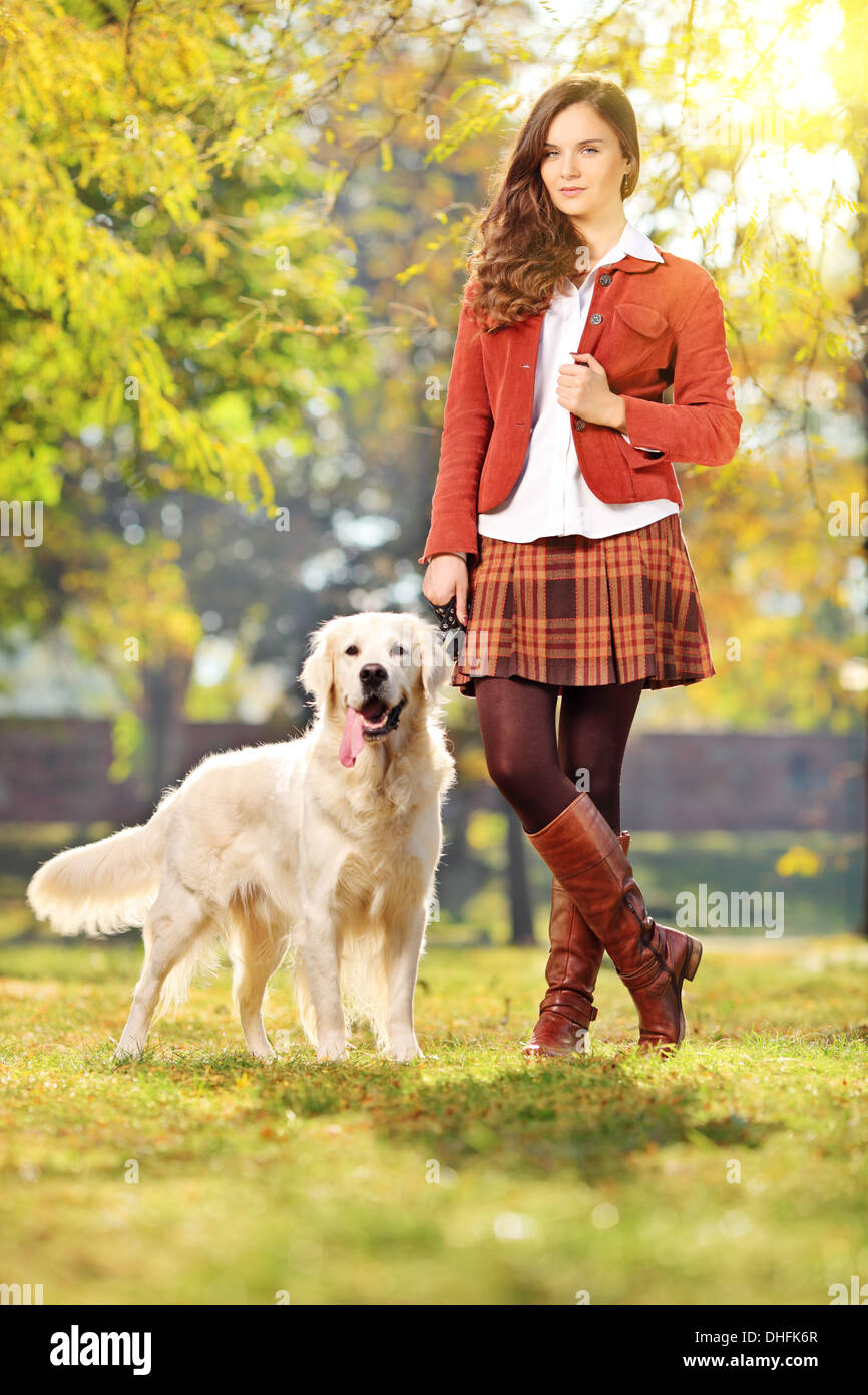 Sorridente giovane donna con il suo cane in un parco Foto Stock