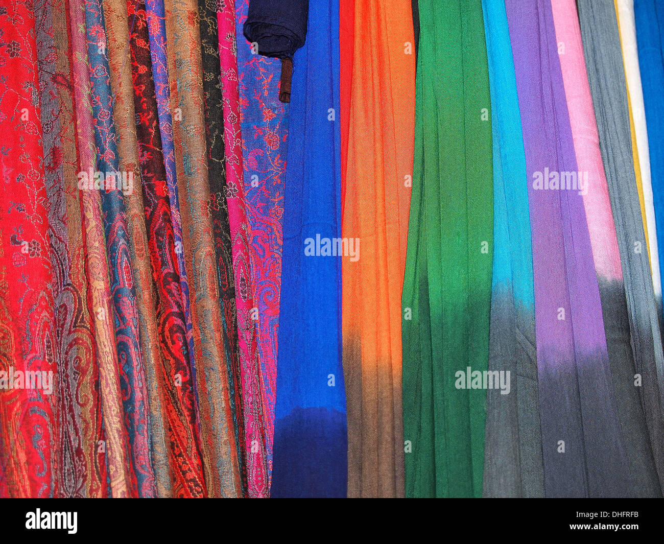 Pila di dolci piegato scialli (sciarpe) appesi al mercato Foto Stock