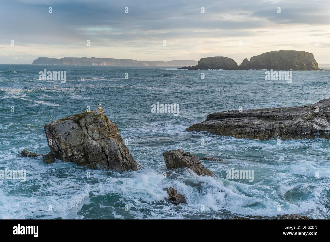 Isola di Rathlin nel distanza come visto da Ballintoy con mare mosso e affioramenti di roccia in primo piano. Foto Stock