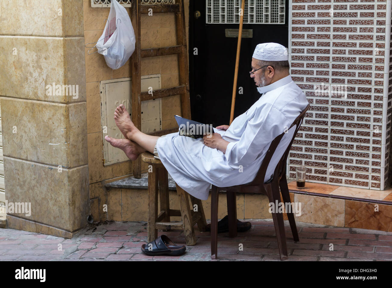 Un uomo seduto sulla strada e la lettura di un libro, Tangeri Foto Stock