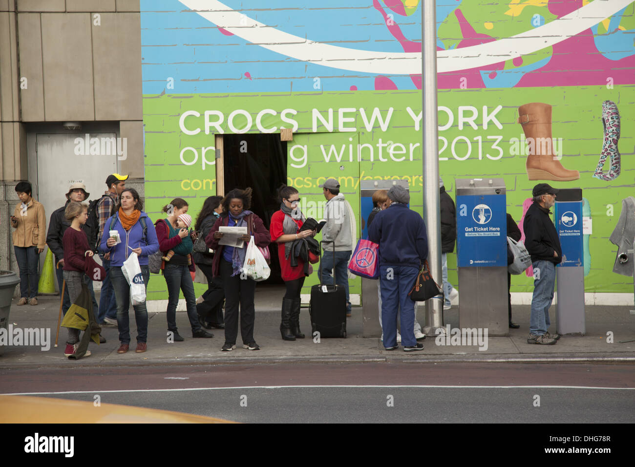 La gente in attesa per un autobus lungo 34th Street a Manhattan NYC. Foto Stock