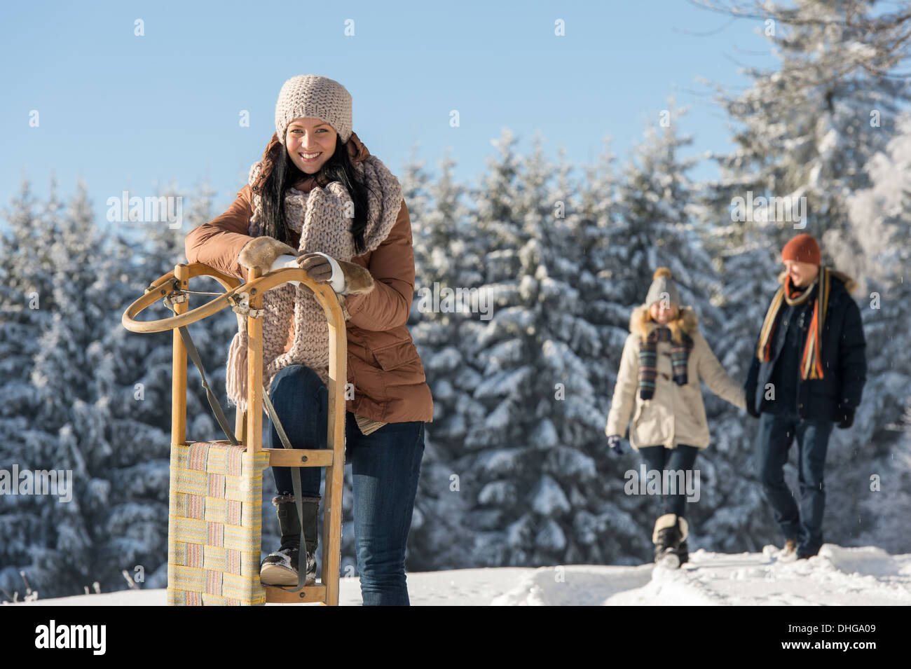 Giovane donna inverno pieno di sole magra contro di legno di neve della slitta Foto Stock