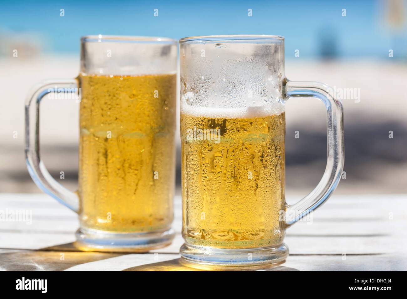 Due bicchieri di birra su di una spiaggia Foto Stock