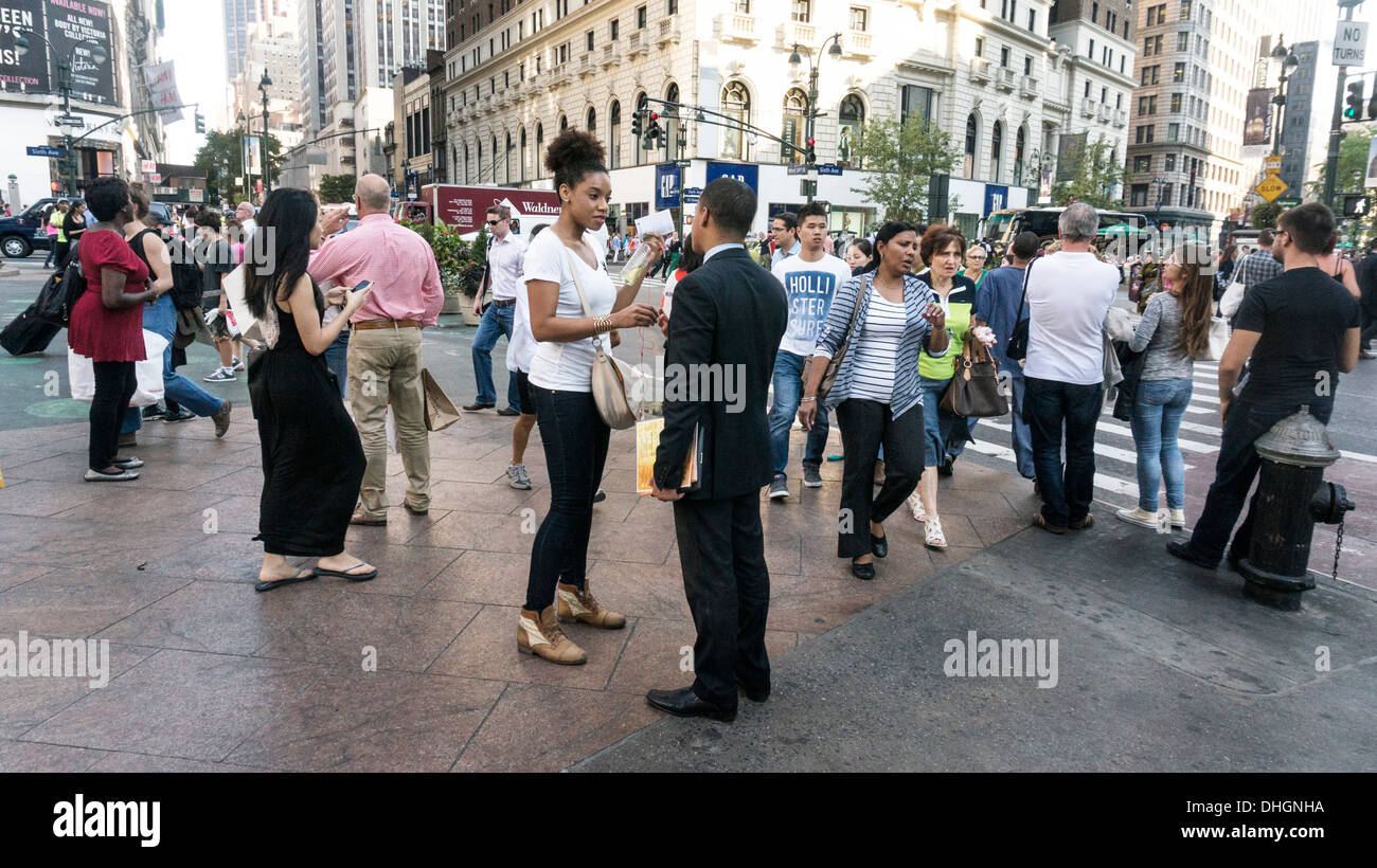 Folla multietnica dei pedoni scramble in tutte le direzioni come le luci cambiare a incrocio occupato di 34th Street e Sixth Avenue Foto Stock