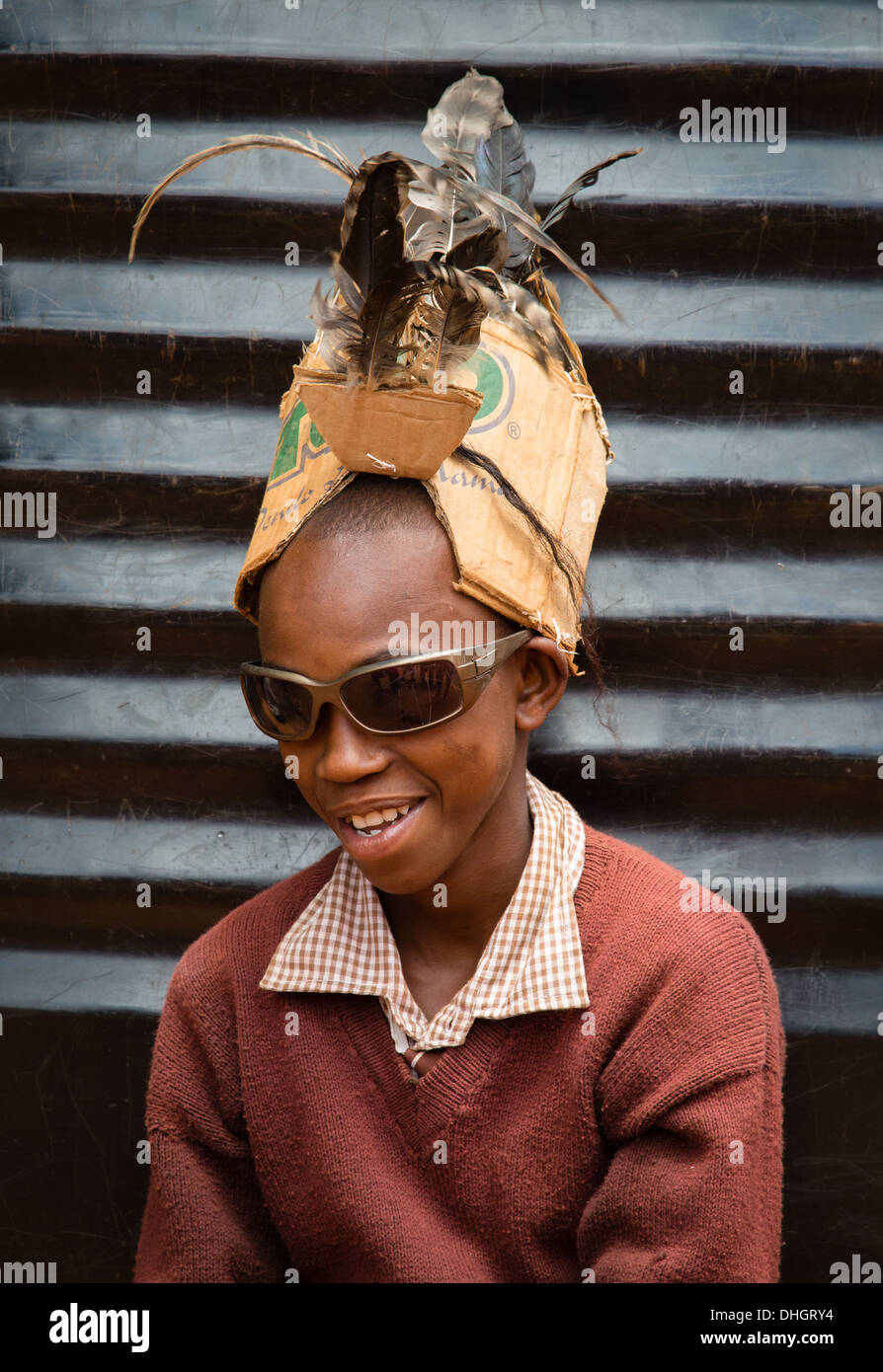 Ragazzo con occhiali da sole e un ripiego cappello piumato realizzata in  cartone riciclato e piume in un keniano scuola primaria Foto stock - Alamy
