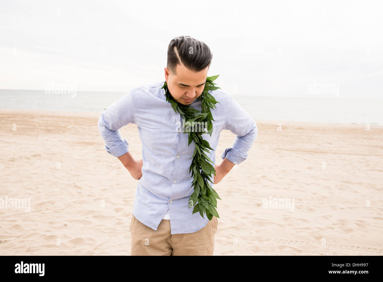 Uomo in piedi sulla spiaggia con fogliame intorno al collo Foto Stock