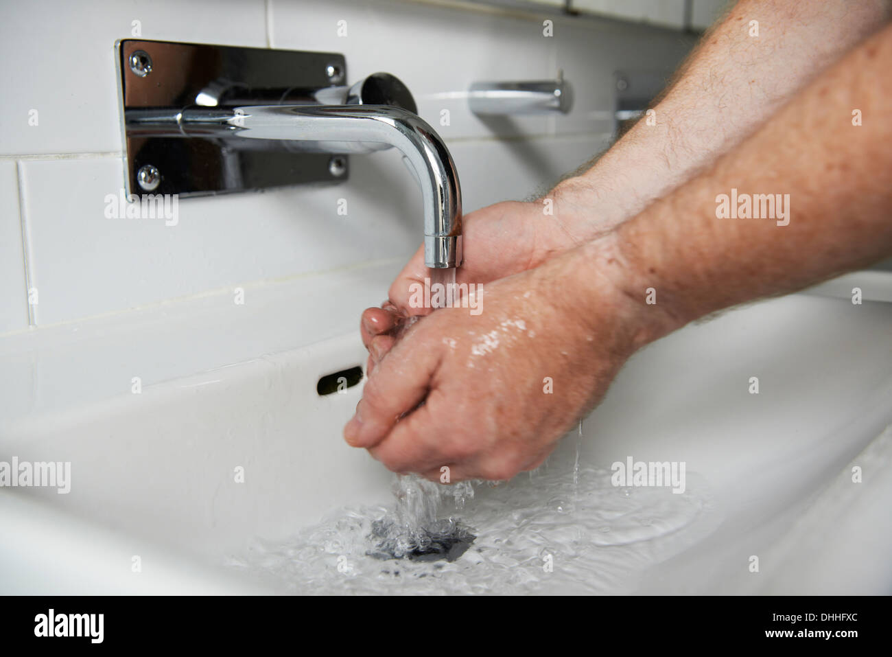 L'uomo lavaggio delle mani in un moderno e bianco lavandino Foto Stock