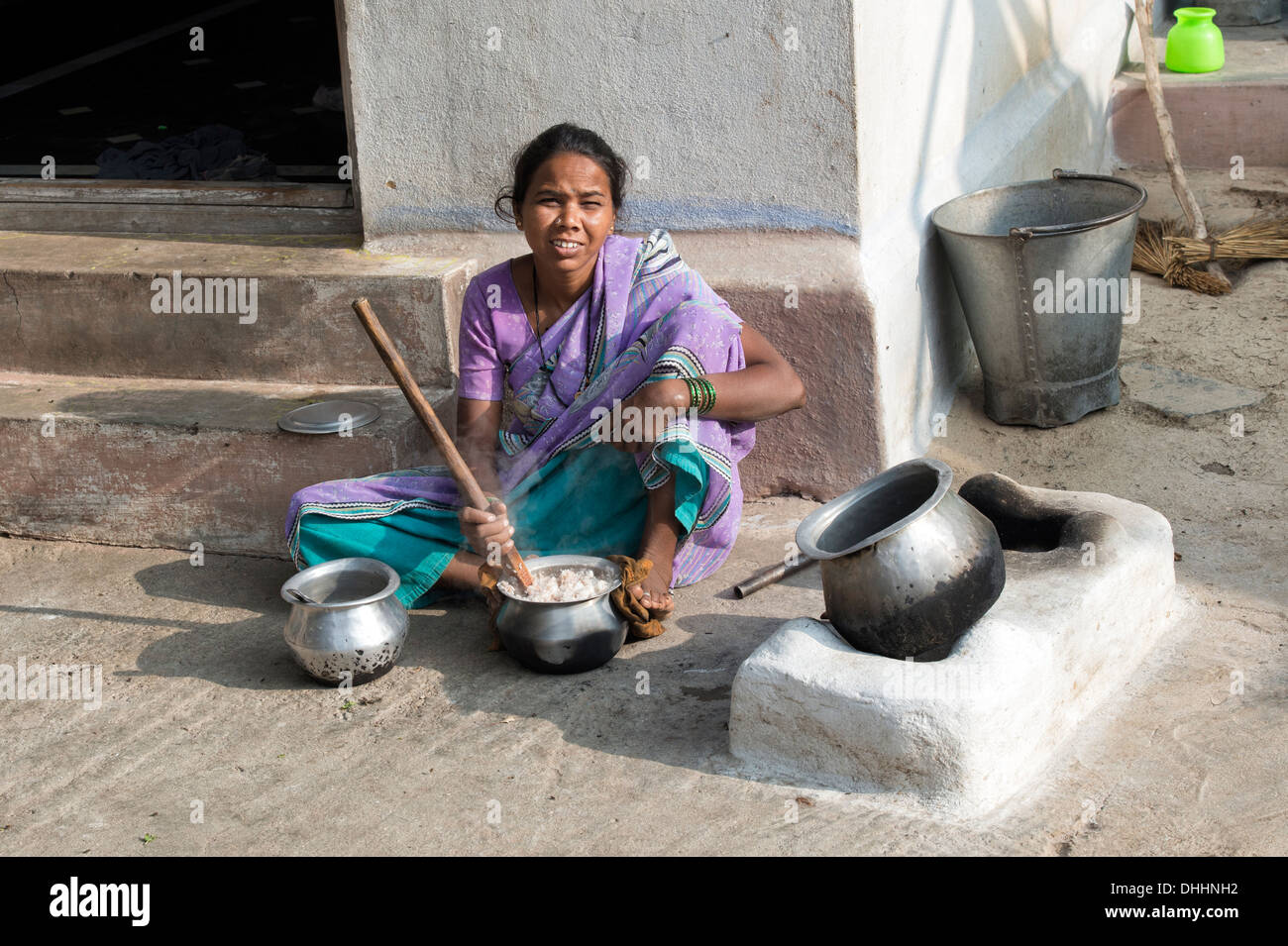 Donna indiana la cottura del riso su un fuoco aperto fuori la sua casa in un borgo rurale. Andhra Pradesh, India Foto Stock