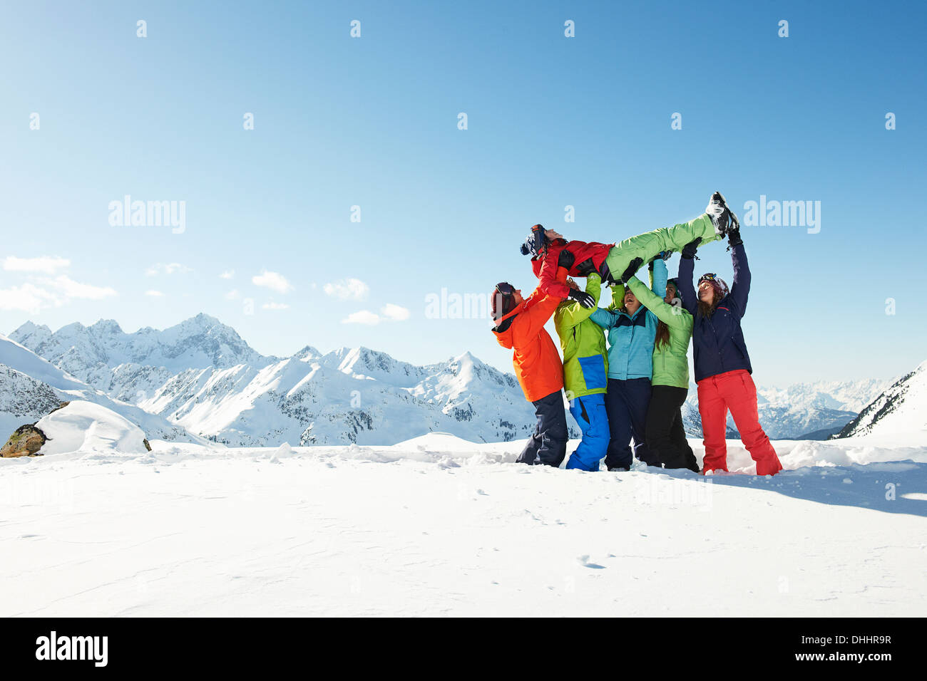 Amici sollevamento di giovane donna nella neve, Kuhtai, Austria Foto Stock