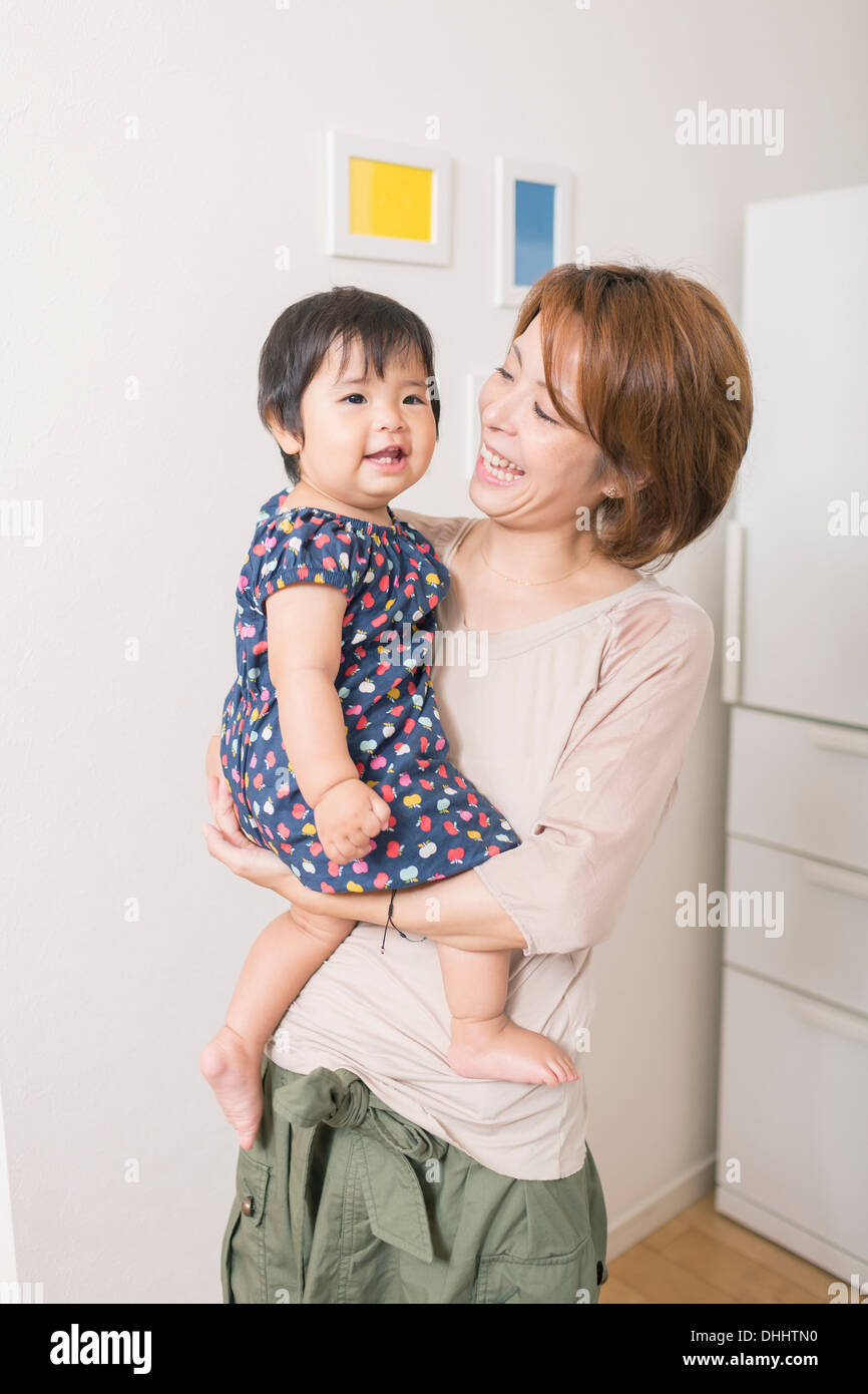 Madre sorridente al bambino nelle braccia Foto Stock