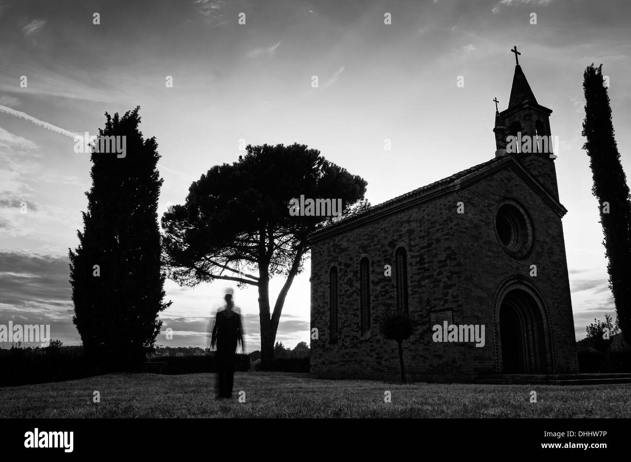Silhouette di persona vicino a una chiesa al crepuscolo Foto Stock
