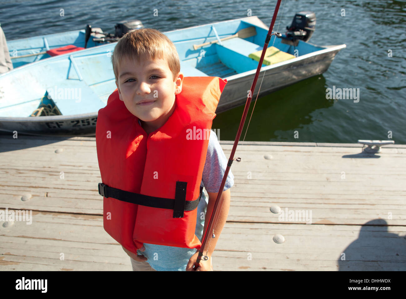 Ragazzo in life jacket in posa con la canna da pesca Foto Stock
