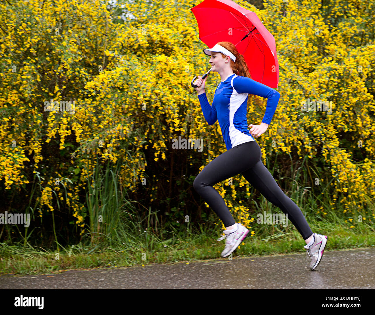 Ragazza adolescente jogging con ombrellone sulla strada, Bainbridge Island, Washington, Stati Uniti d'America Foto Stock
