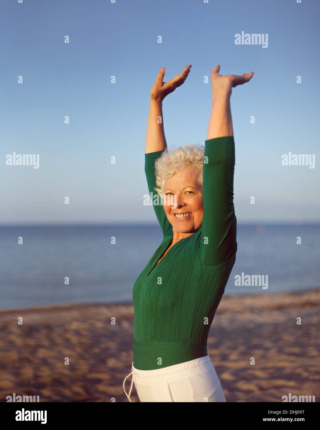 Ritratto di sano donna senior a praticare yoga sulla spiaggia con copyspace. Vecchia donna caucasica esercizio all'aperto per mantenersi in forma. Foto Stock