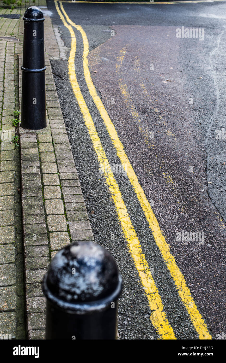 Street bitte e tremolanti a doppia linea gialla, con parziali asfalto e svenuti vecchie linee Foto Stock